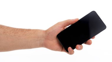 Bir el ileri uzanıyor, siyah ekranlı modern bir akıllı telefon tutuyor. Arka plan bembeyaz. Cihazı ve el tutuşunu vurguluyor..