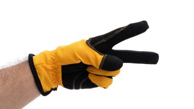 Sarı ve siyah eldiven giyen bir el barış işareti gösterir. Arka plan düz beyaz, eldivenlerin detaylarını ve iyi niyet ve ahenk anlamına gelen jestleri vurguluyor..