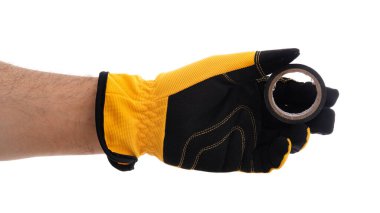 Sarı ve siyah bir eldiven takan güçlü bir elde metal bir yüzük, inşaat veya onarım işleri için alet ve malzemeler sergilenir, bir anlık işçilik ve çabanın altını çizer.