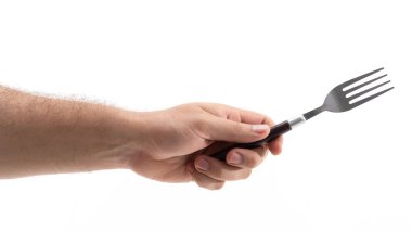 İnsan eli çatalı sıkıca kavrar ve yemeye hazırlanır. Mutfak aleti sade bir arkaplan üzerinde belirgin bir şekilde konumlandırılmış olup, akşam yemeği hareketini vurguluyor..