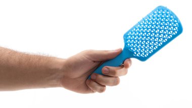 Bir el, mutfak işleri için kullanılan delinmiş yüzeyi olan mavi bir mutfak aletini kavrıyor. Odak noktası çatal, tasarımı ve işlevselliği sergileniyor.