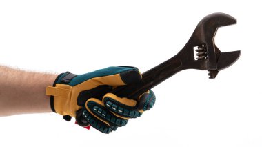 Eldivenli bir el, ayarlanabilir bir anahtarı sıkıca kavrar, mekanik bir görev için hazırdır. Araç, atölye ayarlarında kullanım ve hazırlık durumunu vurgulayan sade bir arkaplan karşısında parıldıyor.