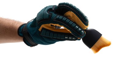 Eldivenli bir el, sanatsal ifade için hazır bir boya fırçasını sıkıca tutar. Fırçanın canlı renkleri, hazırlanma ve odaklanmanın vurgulandığı yaratıcı bir projenin devam ettiğini gösteriyor..