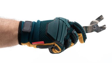 Koruyucu eldiven giyen bir el, metalik bir bahçe aletini kavrayıp, açık hava aktivitelerinde kullanılan güvenlik donanımını gösteriyor. Bu, bahçıvanlık ve bitkilerin bakımına odaklanmayı yansıtır..