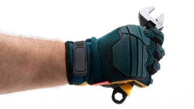 Dayanıklı iş eldiveni giyen bir el ayarlanabilir bir anahtarı sıkıca tutar. El ve araca odaklanmış durumda, çeşitli mekanik görevler ve onarımlara hazır olduğunu gösteriyor.