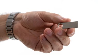 Bir kişi elinde metalik bir USB flaş bellek gösteriyor, parlak ışıklandırma ile depolama cihazının parlak tasarımı ve işlevselliğini vurguluyor.