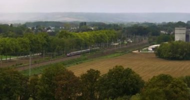 Demiryolunda hızlı giden yolcu treninin hava görüntüsü. Kırsal kesimde yüksek açılı hızlı tren manzarası. Yüksek kalite 4k görüntü