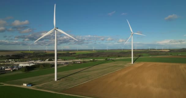 風力からの電力を発生させる大規模な白い発電機 夕日の光の中で雲と青い空に対してフィールドに風力タービン 代替発電 — ストック動画
