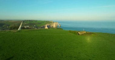 Atlantik kıyısındaki Fransız sınır işaretinin insansız hava aracı görüntüsü. Fransa kıyıları Atlantik Okyanusu ile çevrilidir. Fransa 'da yeşil çayırları olan yüksek uçurumlar. Deniz kıyısında yürüyen insanlar.