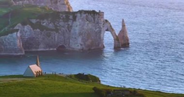 Gün batımında Fransa 'da Atlantik Okyanusu' nun güzel kayalık kıyılarını çekiyoruz. Fransa 'nın en çok ziyaret edilen etkinliklerinden biri olan Etretat' ın modern insansız hava aracı görüntüsü. Okyanustaki yeşil golf sahaları.