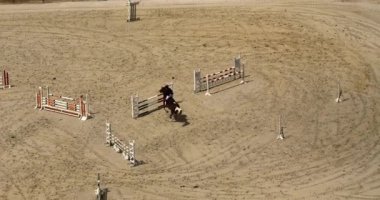 Atların ve binicilerin yarışmaları. At sırtında atlamak. Kumlu parkour binicilik sahasında atlama yarışı, açık havada binicilik yarışması..
