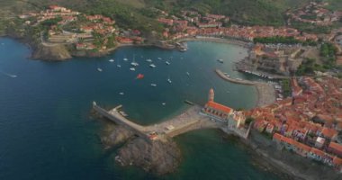  Perpignan yakınlarındaki Collioure kasabasında. Port dAvall plajı ve kraliyet kalesi solda ve deniz feneri sağda. Denizin üzerindeki drone hava görüntüsü.
