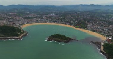 San Sebastian Donostia. La Concha Sahili manzarası ve şehir merkezinin bir kısmı. İHA, La Concha Körfezi üzerinde daireler çiziyor. Tekneler körfezin ortasına yanaştı. Güzel bir turistik yer..