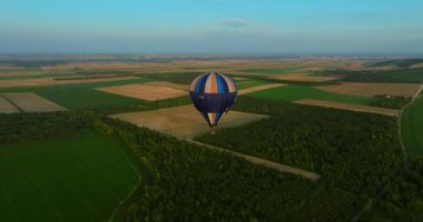 Yeşil manzaranın üzerinde uçan sıcak hava balonu manzarası, ABD. Drone atış balonu. Macera kavramı, eğlence, uçmak. Günbatımı sıcak hava balonu gezisi sahnesini kapatın. Sıcak renkli balon sepeti günbatımı.