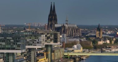 Arka planda kolonya katedrali ve ufuk çizgisi olan bir nehrin yanındaki modern ofis binalarının hava manzarası..