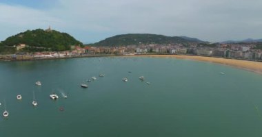San Sebastian Donostia. La Concha Sahili manzarası ve şehir merkezinin bir kısmı. İHA, La Concha Körfezi üzerinde daireler çiziyor. Tekneler körfezin ortasına yanaştı. Güzel bir turistik yer..