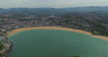 San Sebastian Donostia. La Concha Sahili manzarası ve şehir merkezinin bir kısmı. İHA, La Concha Körfezi üzerinde daireler çiziyor. Tekneler körfezin ortasına yanaştı. Güzel bir turistik yer..