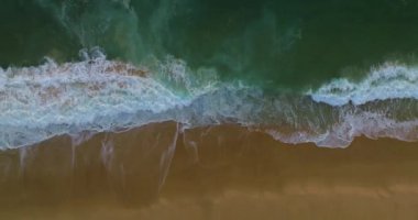 Turkuvaz deniz dalgalarının kumlu kıyı şeridinde hava manzarası. Mavi turkuaz okyanusun yukarıdan görünüşü, dalgalar kırılıyor. Deniz üzerinde güneşli bir gün. Büyük dalgalar kıyıya vuruyor..