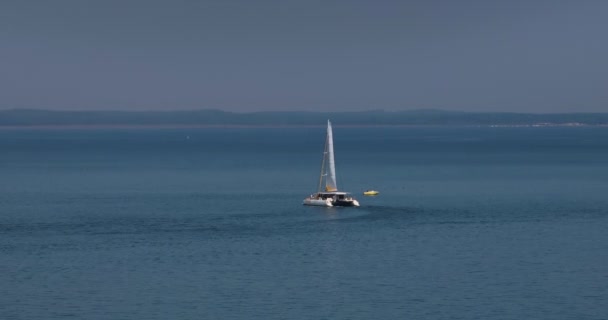 白い目覚めのある深い青い海を航海する豪華な帆船の空の眺め カメラは青い海水のカタマランに従います — ストック動画