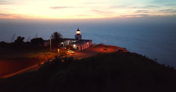 黄昏时分 空中俯瞰着一座坐落在风景如画的岩石上的工作的灯塔 葡萄牙马德拉Ponta Pargo灯塔 — 图库视频影像