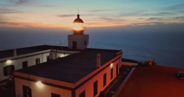 Alacakaranlıkta çalışan deniz fenerine açılan hava manzaralı bir kaya parçası. Deniz feneri Ponta do Pargo, Madeira Portekiz