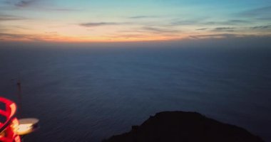 Alacakaranlıkta çalışan deniz fenerine açılan hava manzaralı bir kaya parçası. Deniz feneri Ponta do Pargo, Madeira Portekiz.