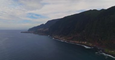 Atlantik Okyanusu 'ndaki yeşil bir adanın kıyısında. Dağlarla ve okyanus kayalıklarıyla Madeira manzarası. Madeira Adası 'nın engebeli kıyı şeridinin nefes kesici manzarası.