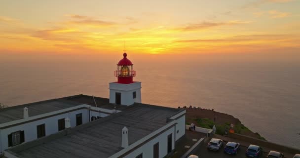 マデイラ ポルトガル サンセットの岩の崖の上の赤と白の灯台の建物への空中ビュー — ストック動画