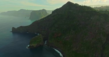 Atlantik Okyanusu 'ndaki yeşil bir adanın kıyısında. Dağlarla ve okyanus kayalıklarıyla Madeira manzarası. Madeira Adası 'nın engebeli kıyı şeridinin nefes kesici manzarası.
