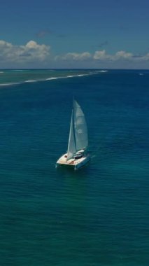 Güzel sakin bir deniz koyundaki katamaran teknesinin havadan görünüşü. Lüks katamaran yatı. Mauritius adası yakınlarında turkuaz suda katamaran. Açık denizde yelken açan katamaranın drone görüntüsü.