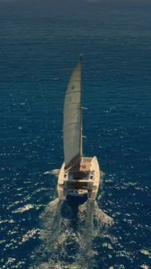 Güzel sakin bir deniz koyundaki katamaran teknesinin havadan görünüşü. Lüks katamaran yatı. Mauritius adası yakınlarında turkuaz suda katamaran. Açık denizde yelken açan katamaranın drone görüntüsü.