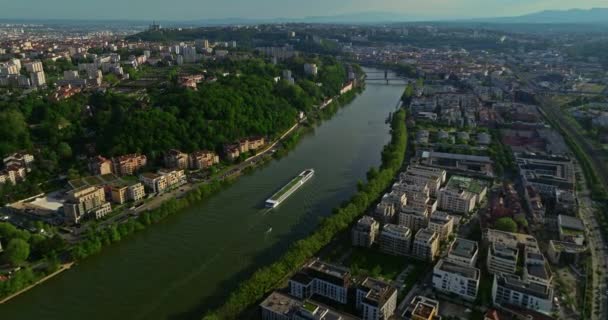 日落时沿着一条蓝色的河流俯瞰城镇 一艘旅游船沿河航行 法国里昂 免版税图库视频