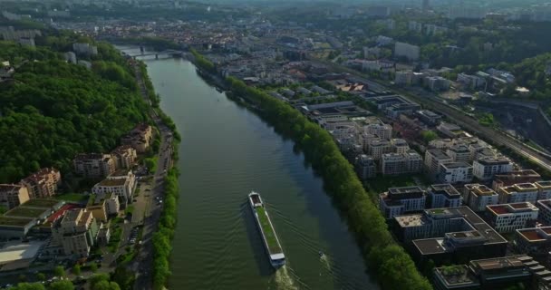 青い川に沿って夕日を眺める街の空中眺望 観光船が川に沿って移動する リヨン フランス — ストック動画