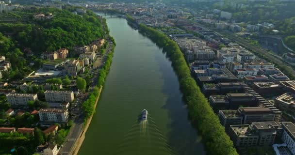 青い川に沿って夕日を眺める街の空中眺望 観光船が川に沿って移動する リヨン フランス — ストック動画