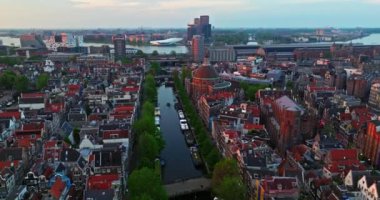 İnsansız hava aracı Amsterdam yaz şehirlerini, dar evleri, kanalları vurdu. Amsterdam, Hollanda 'nın ünlü yerlerinin hava manzarası. Göz kamaştırıcı, keskin çatıların ve modern binaların ön cephelerinin en üst görüntüsü..