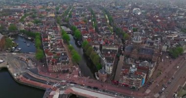 İnsansız hava aracı Amsterdam yaz şehirlerini, dar evleri, kanalları vurdu. Amsterdam, Hollanda 'nın ünlü yerlerinin hava manzarası. Göz kamaştırıcı, keskin çatıların ve modern binaların ön cephelerinin en üst görüntüsü..