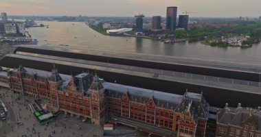 Avrupa turizm şehri Amsterdam 'ın havadan görünüşü. Gün batımında şehir merkezinde bir dron uçuyor. Hollanda 'nın en büyük ve en ünlü şehrinin çekimleri yapılıyor. Dar kanallar şehri böler.