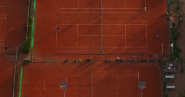 Tenis oyuncuları profesyonel stadyumda maç sırasında hareket halindeler. Hava görüntüsü. Oyuncular kil sahada tenis oynuyorlar.