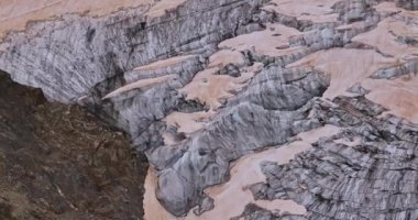 Yüksek dağların arasındaki kadim kar buzulu. Dağların zirveleri karla kaplıdır. İsviçre Alpleri 'nin dağlık arazisi. Drone dağdaki erimiş buzullara doğru yavaşça uçuyor..
