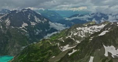 Yüksek dağların arasındaki kadim kar buzulu. Dağların zirveleri karla kaplıdır. İsviçre Alpleri 'nin dağlık arazisi. Drone dağdaki erimiş buzullara doğru yavaşça uçuyor..