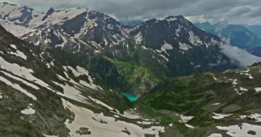 Yüksek dağların arasındaki kadim kar buzulu. Dağların zirveleri karla kaplıdır. İsviçre Alpleri 'nin dağlık arazisi. Drone dağdaki erimiş buzullara doğru yavaşça uçuyor..