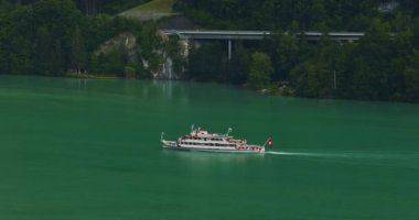 Lucerne Gölü 'ndeki buharlı geminin insansız hava aracı görüntüsü. İsviçre Bayrağı. İsviçre 'de yaz mevsiminde güzel İsviçre Alpleri doğası. Turkuaz mavi göl suyu.