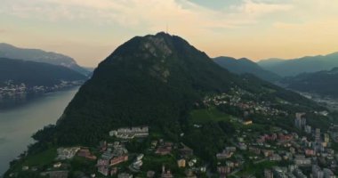 Lugano şehrinin havadan görünüşü ve San Salvatore dağından Lugano Gölü. İsviçre, Canton Ticino 'daki Lugano şehrine bakan Monte Bre' nin hava görüntüleri..