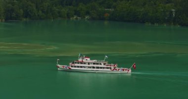 Göl kenarındaki hava manzaralı buharlı gemi İsviçre bayrağıyla Alplerdeki güzel bir gölün turkuaz suyunda yürüyor..