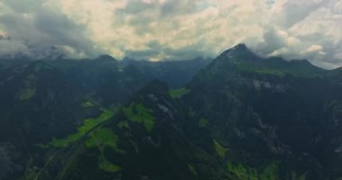 İnsansız hava aracı, arkasında dağlar olan yeşil renkli vadilerin üzerinden uçuyor. Yüksek Dağlar İsviçre 'nin ünlü simgeleridir. İsviçre 'deki Idyllic dağ manzarası, İsviçre kırsal havası.