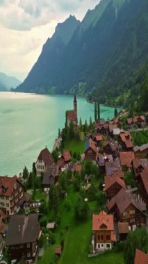 Alpler arasındaki gölün kıyısındaki geleneksel İsviçre evlerinin insansız hava aracı görüntüsü. Brienz, İsviçre. İsviçre 'nin Brienz şehrinin insansız hava aracı görüntüleri. Yazın İsviçre 'yi gezmek.
