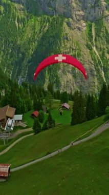 Paraglider 'ın İsviçre' deki dağlık dağlarda üzerinde İsviçre bayrağı olan hava manzarası..