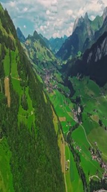 İnsansız hava aracı, arkasında dağlar olan yeşil renkli vadilerin üzerinden uçuyor. Yüksek Dağlar İsviçre 'nin ünlü simgeleridir. İsviçre 'deki Idyllic dağ manzarası, İsviçre kırsal havası.