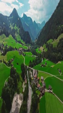 İnsansız hava aracı, arkasında dağlar olan yeşil renkli vadilerin üzerinden uçuyor. Yüksek Dağlar İsviçre 'nin ünlü simgeleridir. İsviçre 'deki Idyllic dağ manzarası, İsviçre kırsal havası.