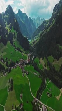 İnsansız hava aracı, arkasında dağlar olan yeşil renkli vadilerin üzerinden uçuyor. Yüksek Dağlar İsviçre 'nin ünlü simgeleridir. İsviçre 'deki Idyllic dağ manzarası, İsviçre kırsal havası.